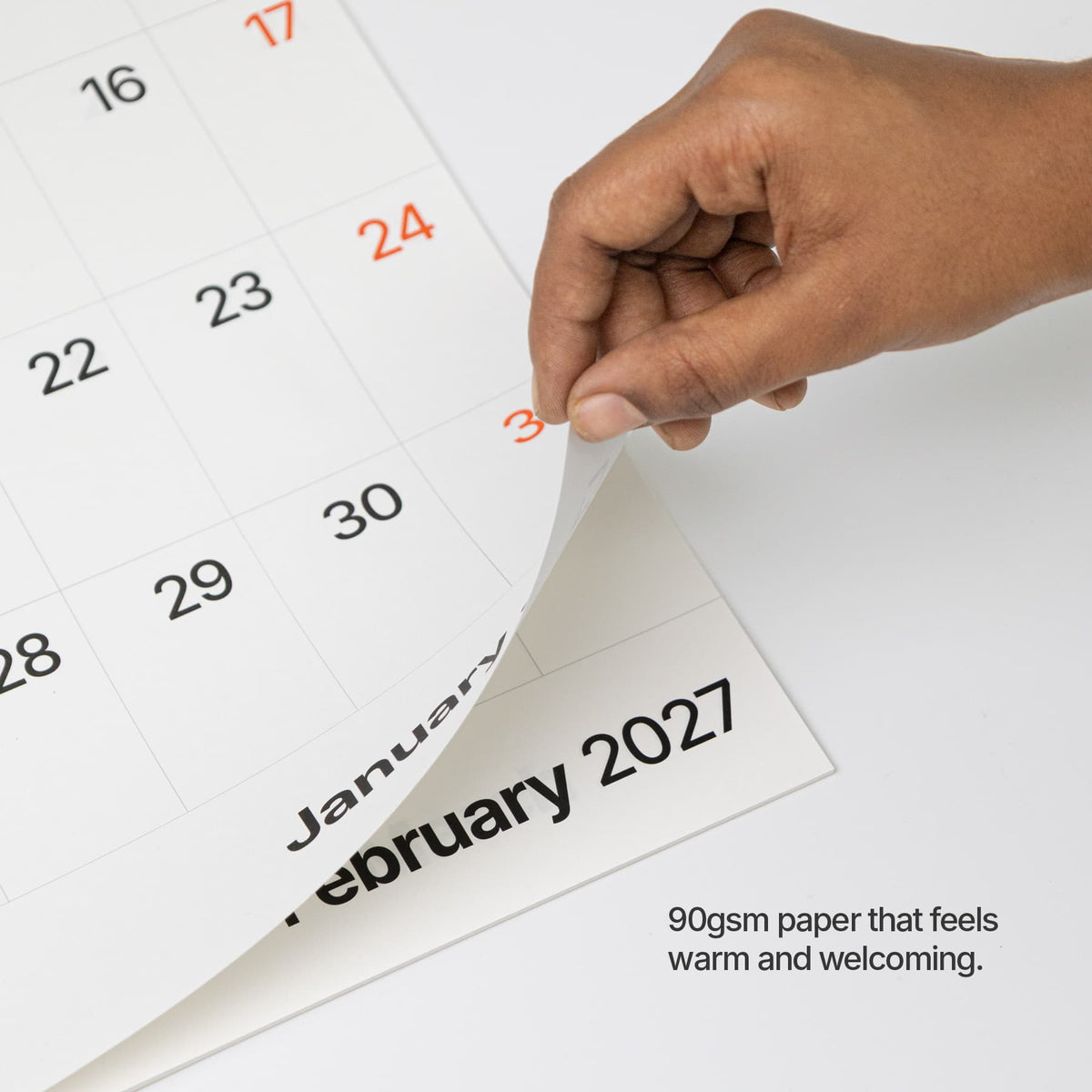 Paper close-up: Hand lifting a 90 gsm paper sheet on the Roda 2027 wall calendar.