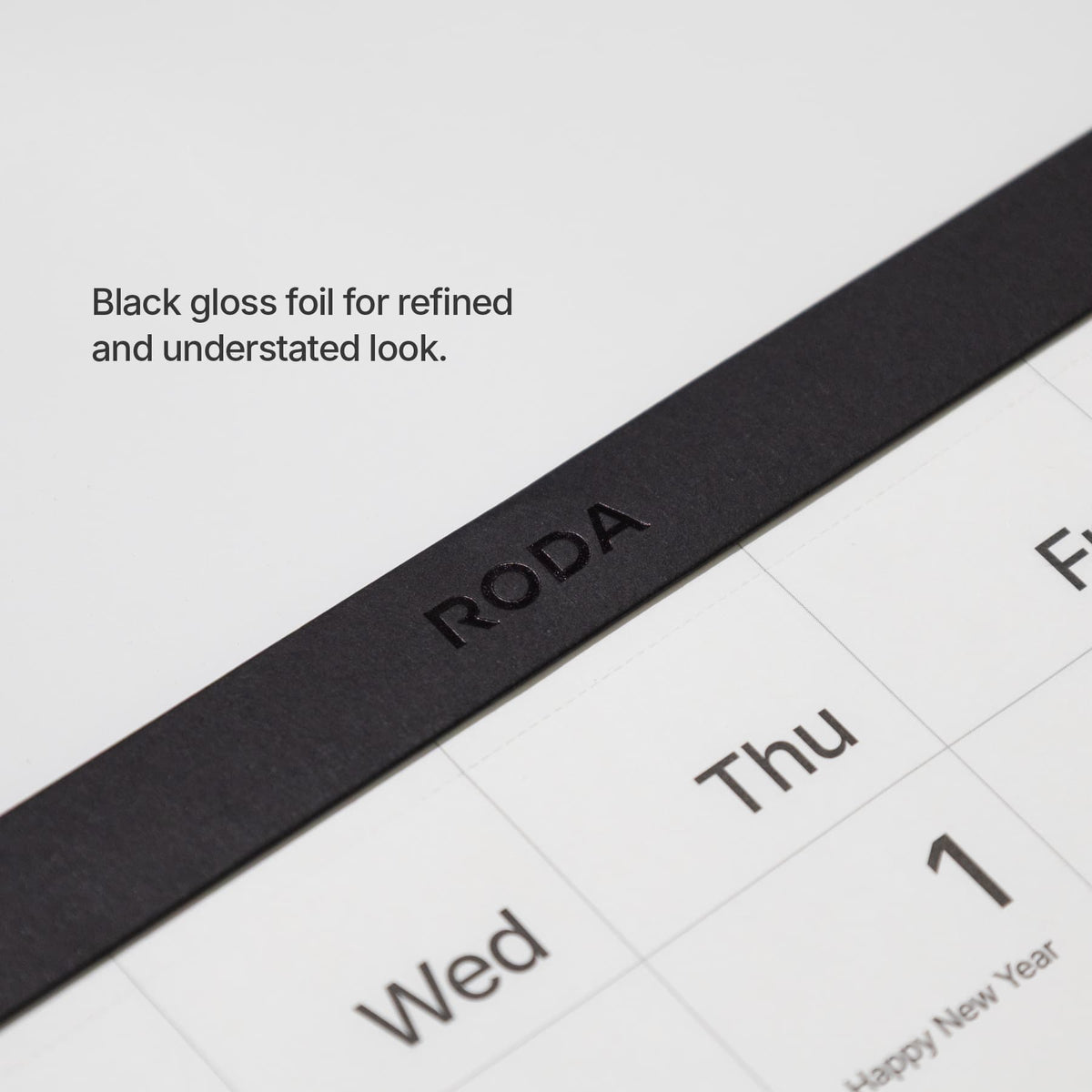 Logo detail: Close-up of the black gloss-foil Roda logo on the wall calendar header.