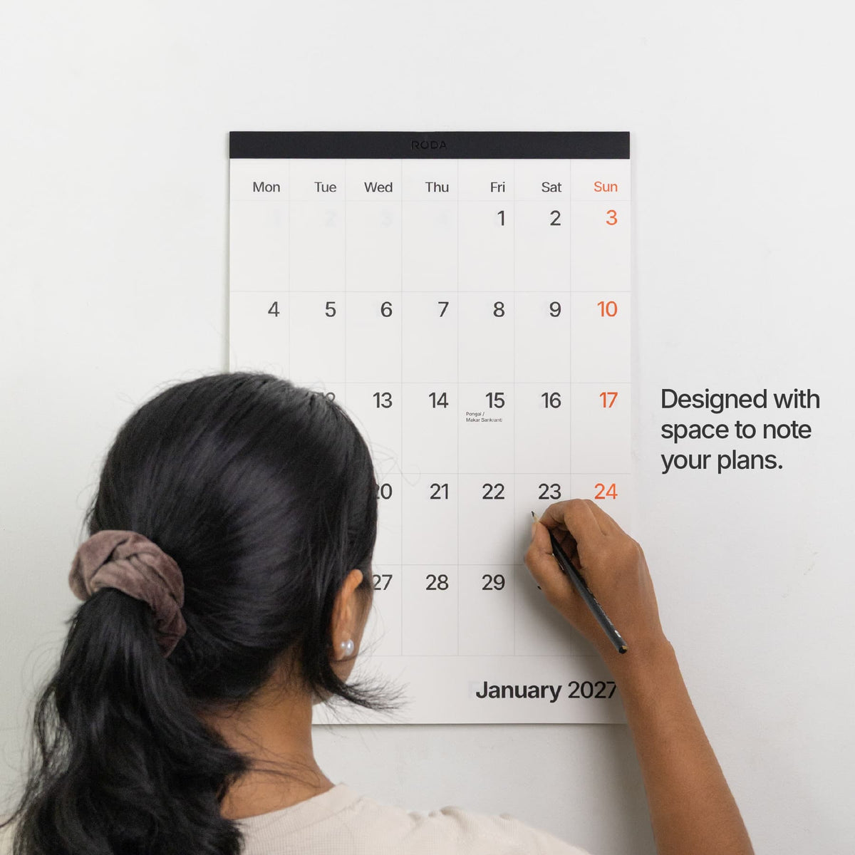 Space for notes: Person writing plans on the January page of the Roda 2027 wall calendar.